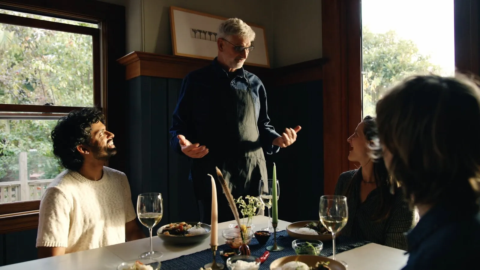 Friends talking around a candlelit dinner table after cooking together
