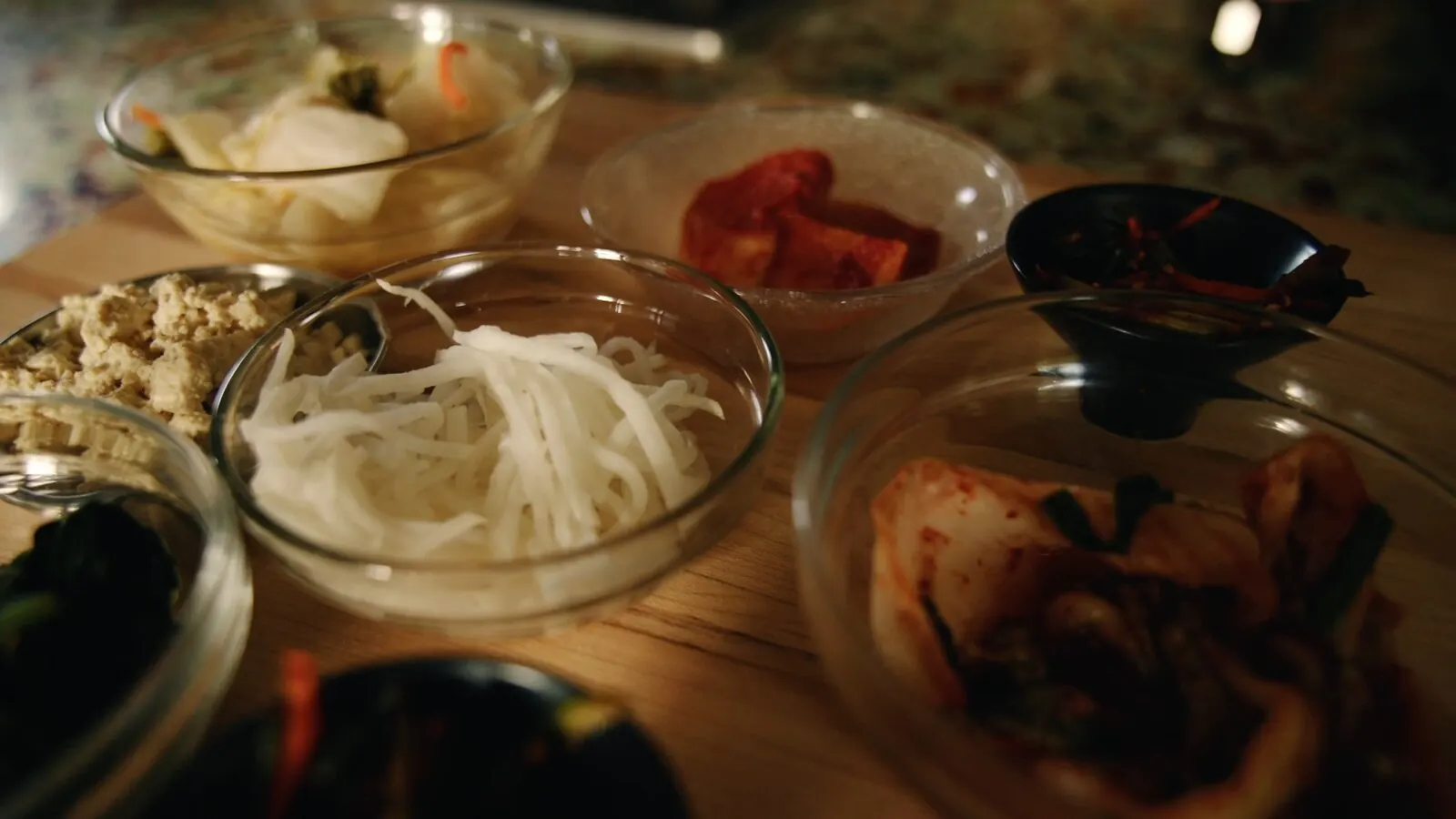 Prepped ingredients in glass bowls on a wooden counter before cooking