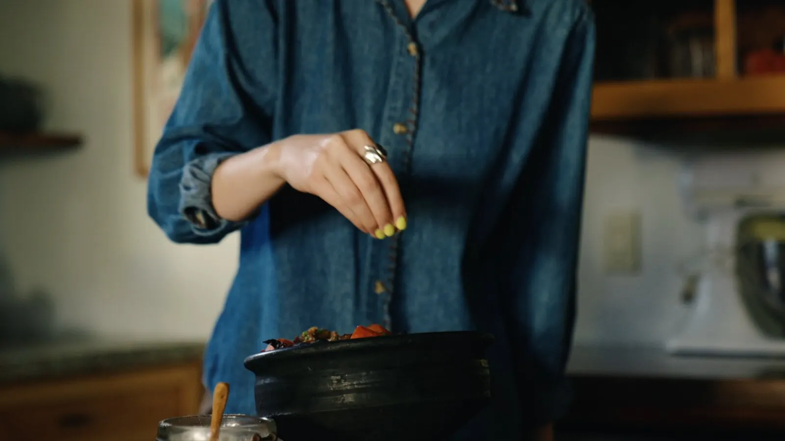 A home cook seasons a pot by hand, salting from the fingers